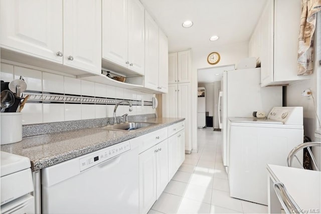 kitchen featuring white appliances, sink, light tile patterned floors, separate washer and dryer, and white cabinets