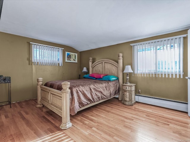 bedroom featuring a baseboard radiator, light hardwood / wood-style flooring, and lofted ceiling