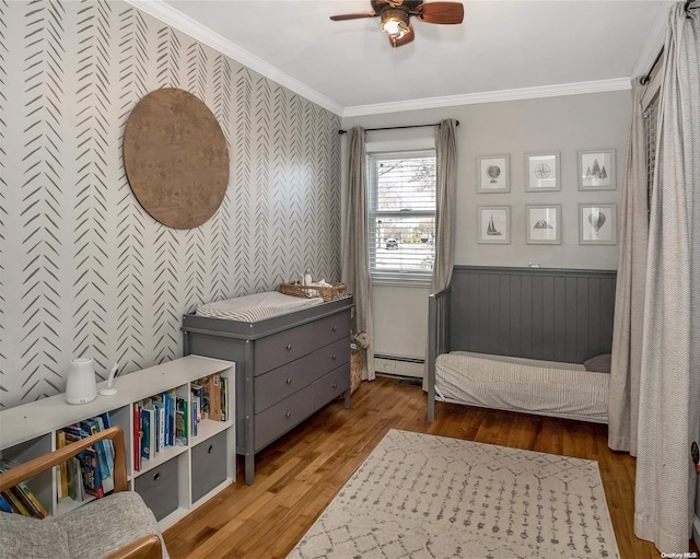 sitting room with ceiling fan, wood-type flooring, crown molding, and baseboard heating