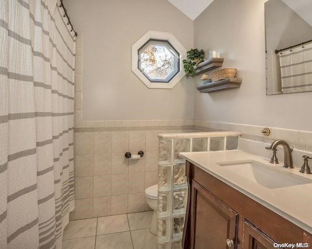 bathroom with vanity, tile walls, tile patterned flooring, toilet, and lofted ceiling