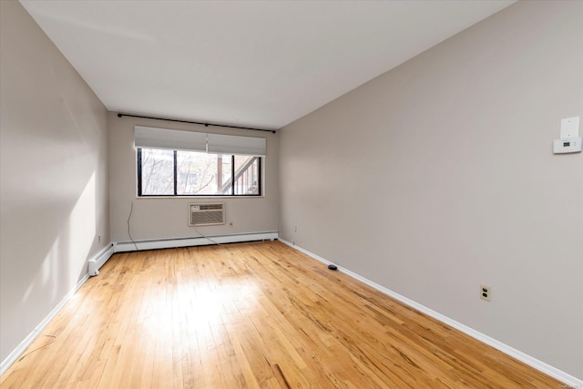 spare room featuring a baseboard radiator, a wall unit AC, and light wood-type flooring