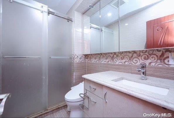 bathroom with vanity, toilet, and a shower with shower door