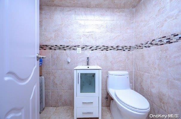 bathroom featuring toilet, tile walls, and sink