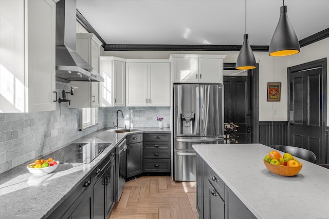 kitchen featuring sink, wall chimney range hood, light stone counters, white cabinets, and appliances with stainless steel finishes