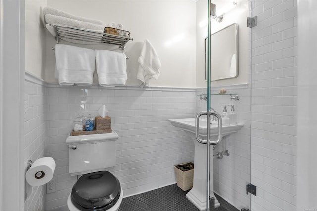 bathroom featuring tile patterned floors, toilet, and tile walls