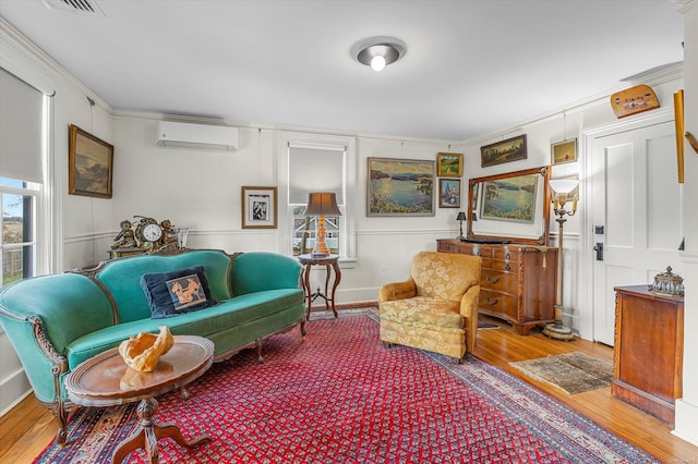 living area with wood-type flooring, a wall unit AC, and ornamental molding