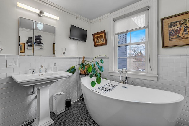 bathroom with a washtub, tile patterned floors, tile walls, and ornamental molding