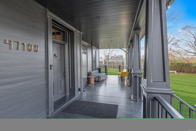 wooden terrace featuring covered porch and a yard