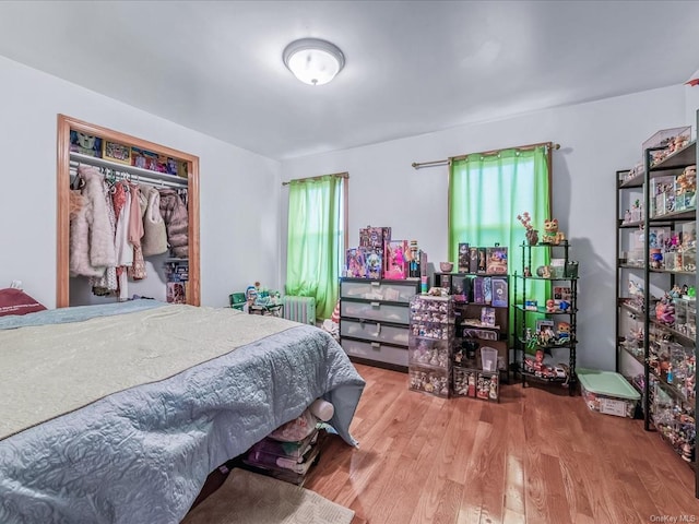 bedroom featuring wood-type flooring, radiator, and a closet