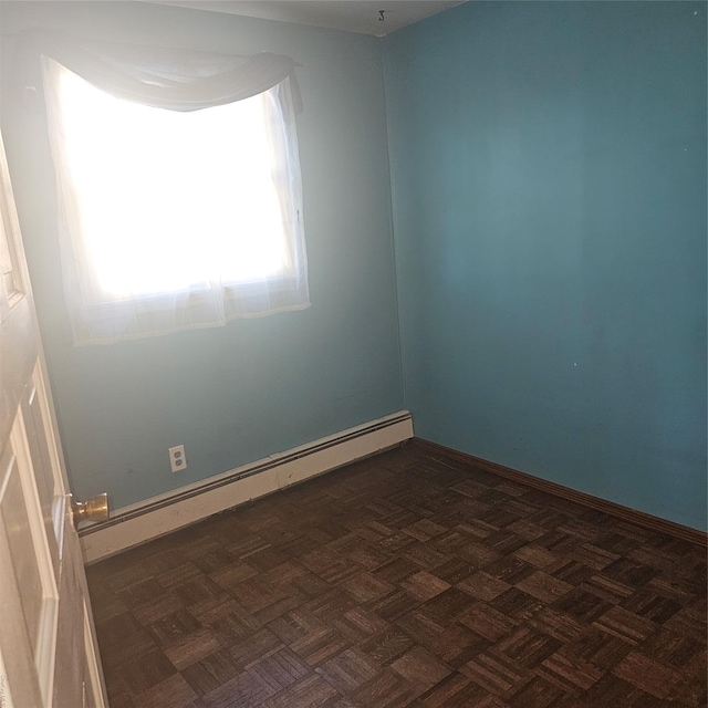 empty room featuring baseboard heating and dark parquet flooring