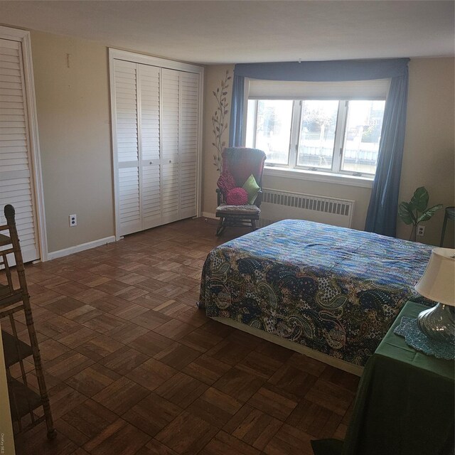 bedroom featuring radiator heating unit, dark parquet floors, and a closet