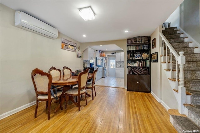 dining area featuring a wall mounted air conditioner and light wood-type flooring