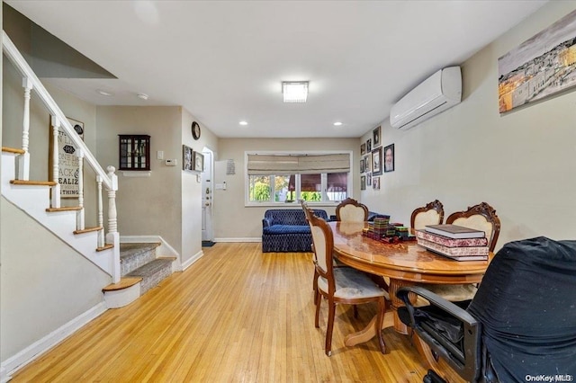 dining area with light hardwood / wood-style floors and a wall unit AC