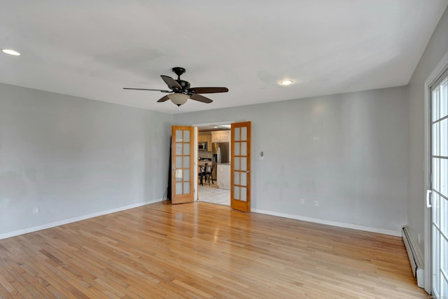 unfurnished room featuring baseboard heating, ceiling fan, french doors, and light wood-type flooring