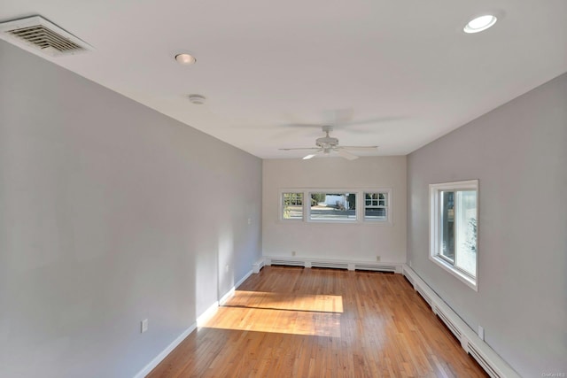 spare room with light wood-type flooring, ceiling fan, and a baseboard heating unit