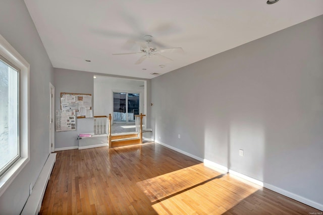 unfurnished room with ceiling fan, wood-type flooring, and baseboard heating