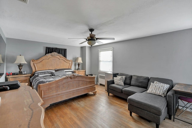 bedroom with radiator, light hardwood / wood-style flooring, and ceiling fan