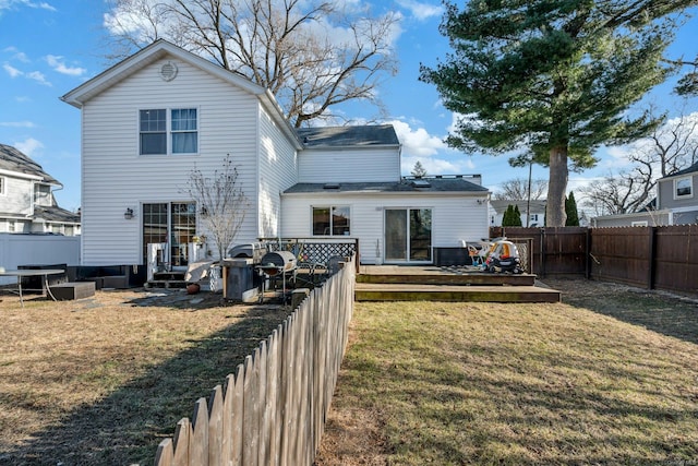 back of house featuring a lawn and a wooden deck