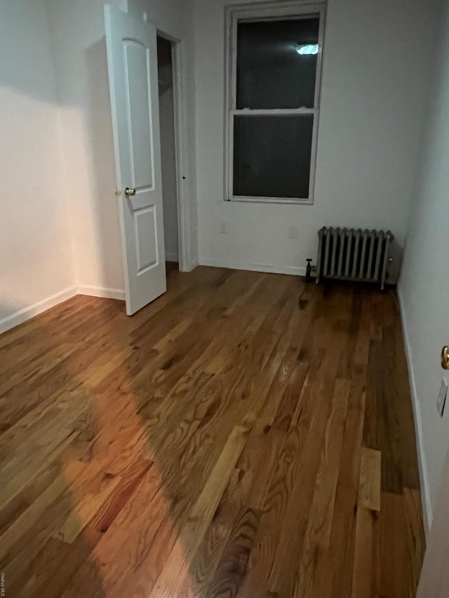 empty room featuring hardwood / wood-style floors and radiator heating unit