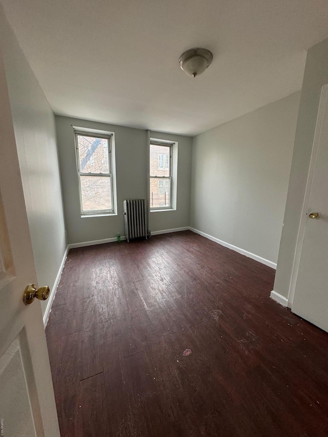 unfurnished room featuring radiator and dark hardwood / wood-style floors