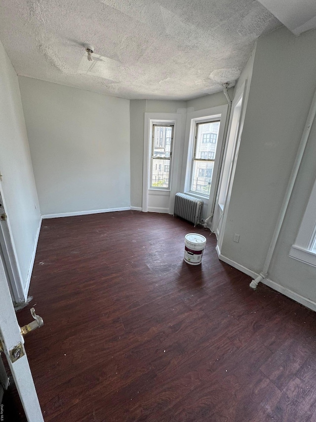 unfurnished room featuring radiator, dark hardwood / wood-style flooring, and a textured ceiling