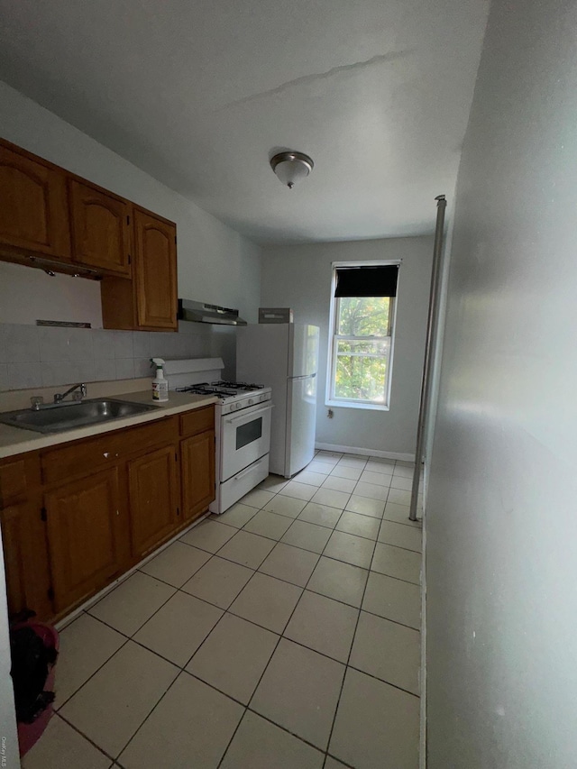 kitchen featuring white appliances, backsplash, sink, light tile patterned floors, and extractor fan