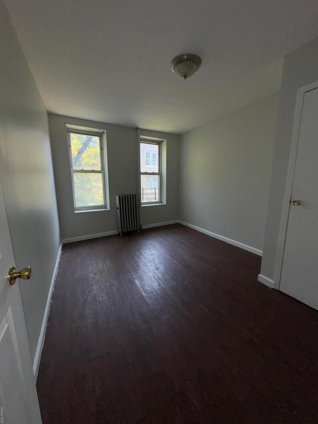 empty room featuring radiator heating unit and dark wood-type flooring