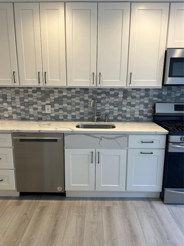 kitchen featuring white cabinets, stainless steel appliances, tasteful backsplash, and sink