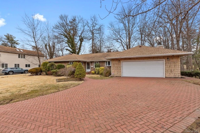 view of front facade with a garage, a chimney, decorative driveway, and a front yard