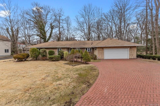 ranch-style house with an attached garage, a front lawn, and decorative driveway