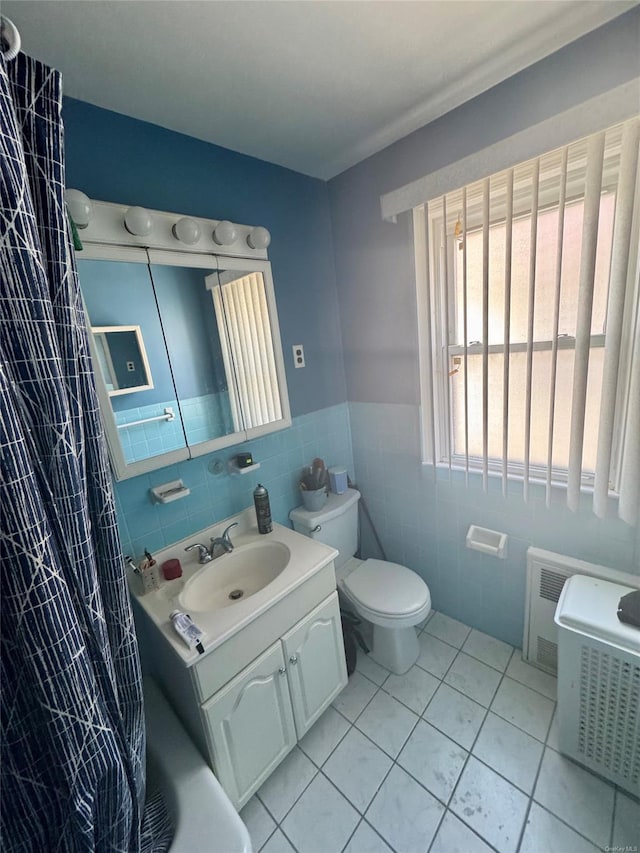 bathroom featuring vanity, toilet, tile patterned flooring, and tile walls