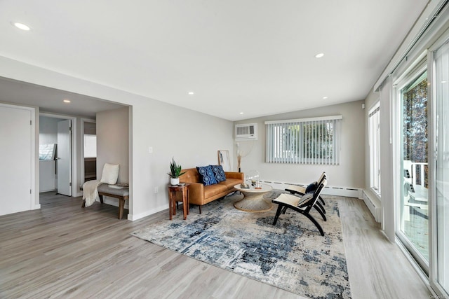 sitting room with plenty of natural light, light wood-type flooring, and an AC wall unit