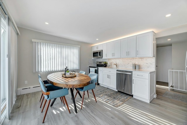 kitchen featuring white cabinets, a healthy amount of sunlight, light wood-type flooring, and appliances with stainless steel finishes