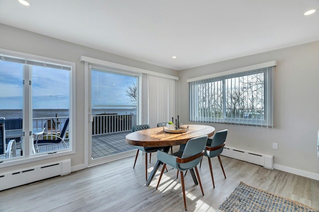 dining room featuring light hardwood / wood-style flooring, a wealth of natural light, and a baseboard radiator