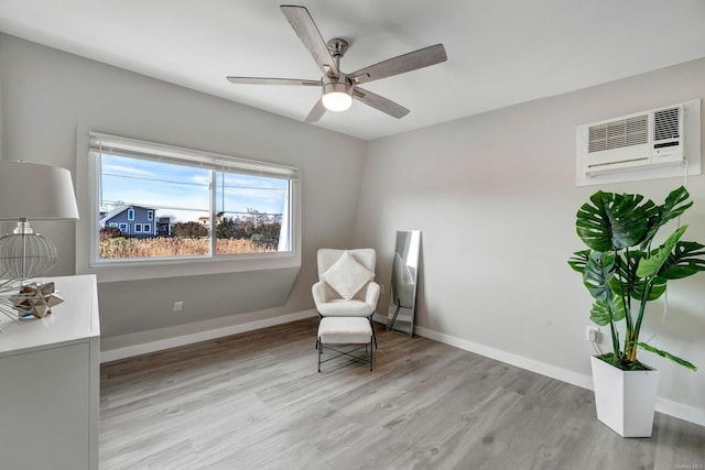 living area featuring a wall mounted AC, ceiling fan, and light hardwood / wood-style flooring