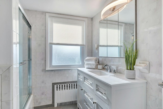 bathroom with shower / bath combination with glass door, radiator heating unit, and tile walls