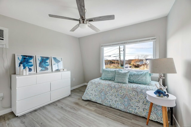 bedroom featuring ceiling fan, light hardwood / wood-style flooring, and a wall mounted air conditioner