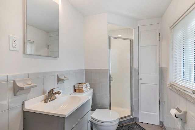 bathroom with vanity, toilet, an enclosed shower, and tile walls