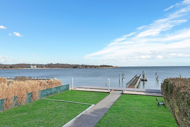 view of dock featuring a lawn and a water view