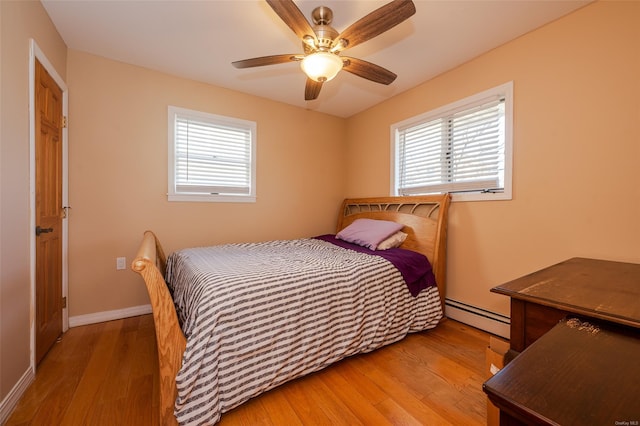 bedroom featuring light wood-type flooring, ceiling fan, and a baseboard heating unit