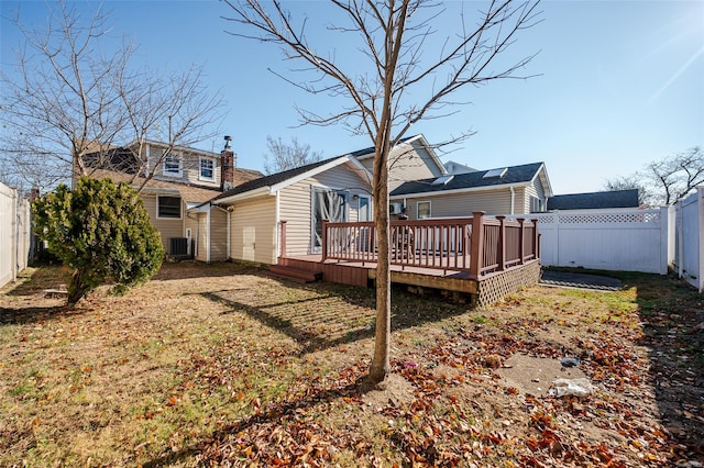 rear view of property featuring a deck, central AC unit, and a lawn