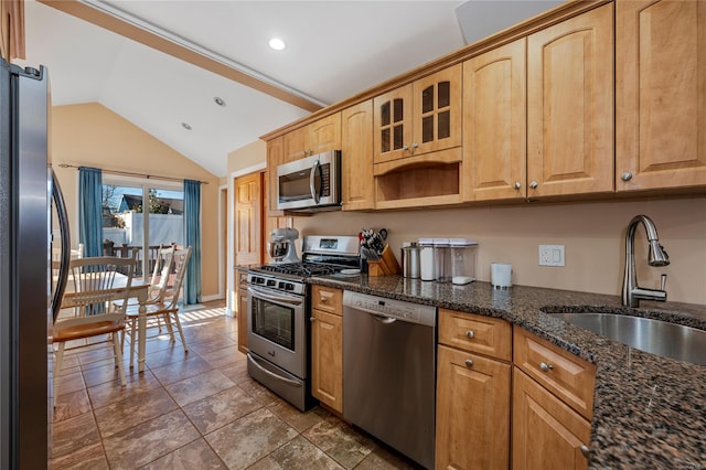 kitchen featuring sink, lofted ceiling, stainless steel appliances, and dark stone counters