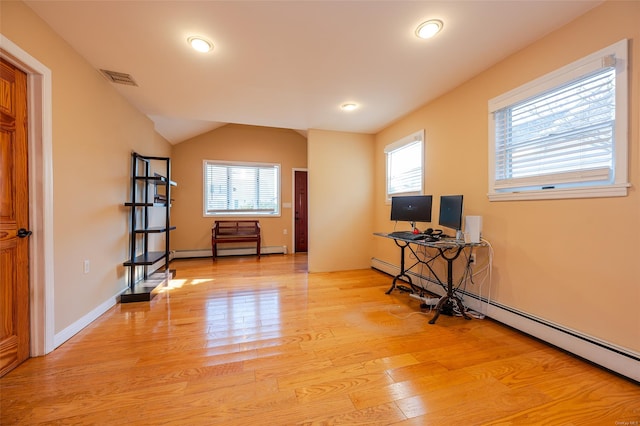 interior space with a baseboard heating unit, a wealth of natural light, and light hardwood / wood-style flooring