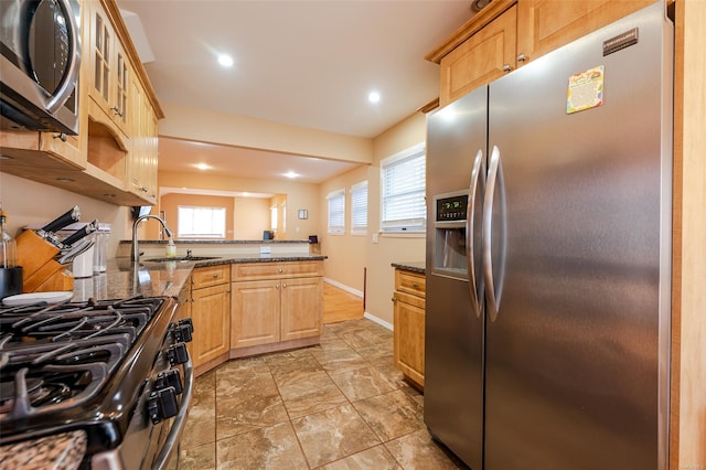 kitchen with light brown cabinets, stainless steel appliances, dark stone counters, and sink