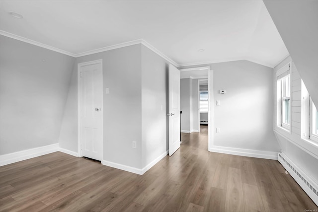 additional living space featuring wood-type flooring, a baseboard heating unit, and vaulted ceiling