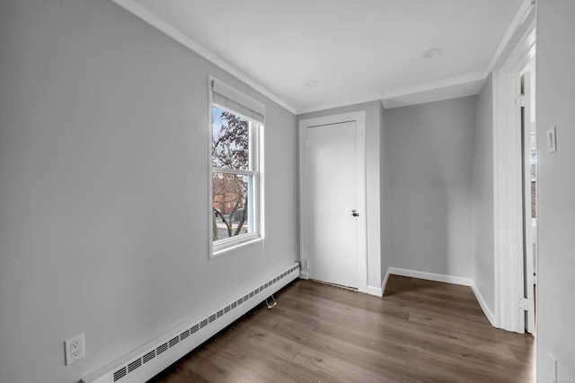 unfurnished bedroom featuring a baseboard heating unit, wood-type flooring, and multiple windows