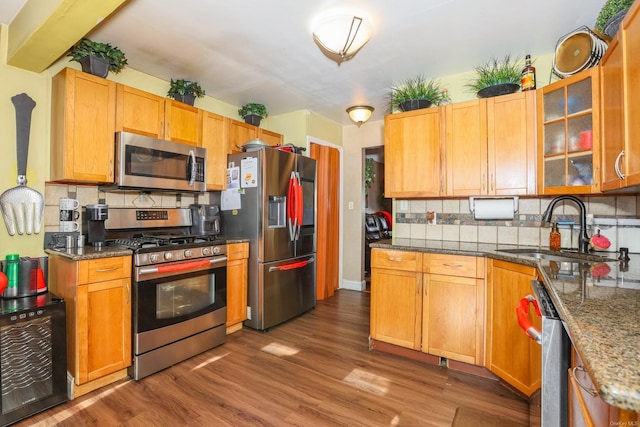 kitchen featuring appliances with stainless steel finishes, backsplash, hardwood / wood-style flooring, and sink