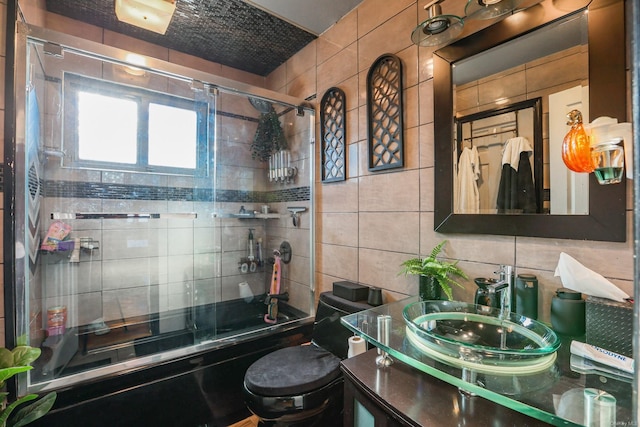 full bathroom featuring decorative backsplash, vanity, shower / bath combination with glass door, tile walls, and toilet