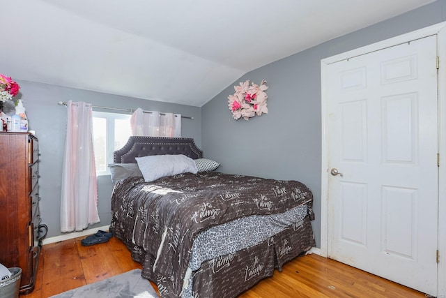 bedroom with wood-type flooring and vaulted ceiling