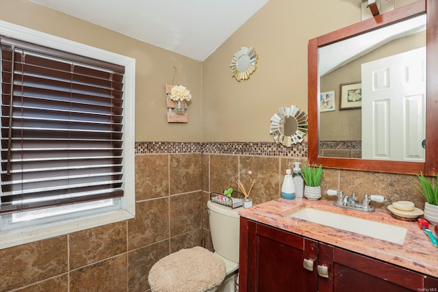 bathroom with vanity, toilet, tile walls, and lofted ceiling